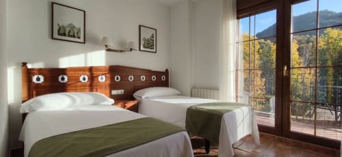 Moderna habitación doble en Hospedería Puerta a los Cahorros con vistas a montaña, camas gemelas, cabecero de madera y terraza