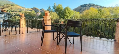 Terraza de montaña con sillas en Hospedería Puerta a los Cahorros de Monachil, rodeada de verdes colinas y valles