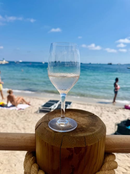 Verre de champagne sur poteau en bois face à la plage de Cannes et la Méditerranée turquoise