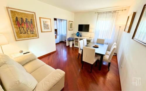 Bright apartment living room with dining table, cream sofa, hardwood floors, and framed artwork in Padova historic center