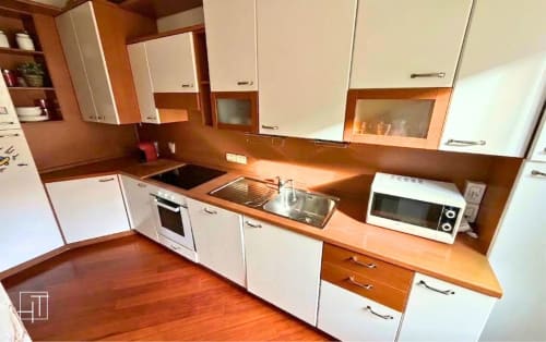Modern kitchen in Padova apartment with wooden countertops, white cabinets, stove, sink, and microwave