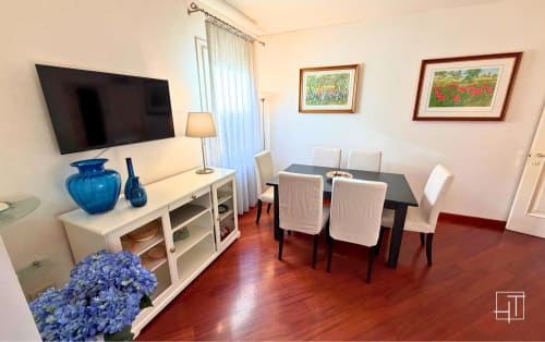 Modern apartment living and dining area with flat-screen TV, wood furniture, blue accents, and framed art in Padova historic