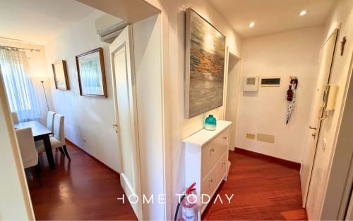 Bright apartment hallway with red wooden floors, white doors, and modern fixtures in Padova's historic center