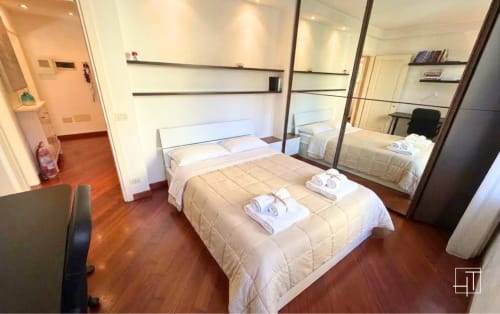 Modern bedroom with wooden floors, mirrored wardrobe, and white bedding at Hometoday apartment in Padova historic center