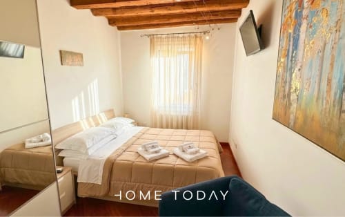 Cozy bedroom at Hometoday Santa Sofia, Padova with wooden beams, double bed, and city view window