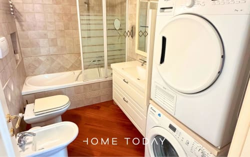 Hometoday apartment bathroom with toilet, bidet, bathtub with shower, sink, and stacked washer-dryer in Padova