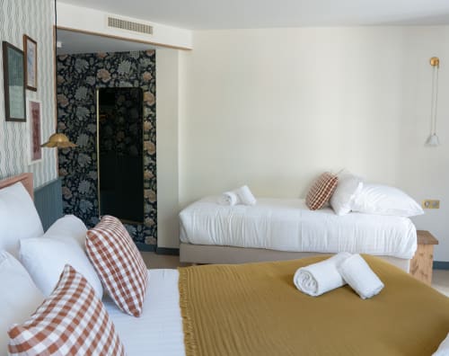 Chambre triple lumineuse à l'Hôtel Saint Enogat à Dinard avec deux lits, oreillers à carreaux et décor nautique moderne