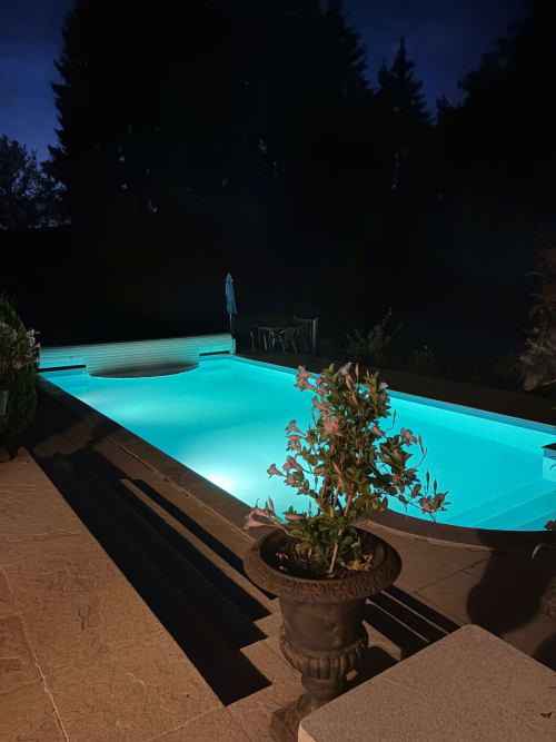 Illuminated turquoise pool at night surrounded by forest at L'Instant Sauvage cottage, Dun les Places