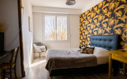 Quarto tropical em Maison de Barlest em Barlest com papel de parede em dourado com palmas, cabeceira azul e vista para a montanha