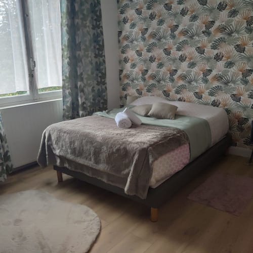 Quarto luminoso na Maison de Barlest com papel de parede tropical, luz natural e cama arrumada