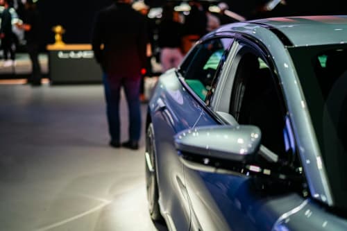 Voiture moderne exposée au salon automobile de Lyon avec des visiteurs flous en arrière-plan