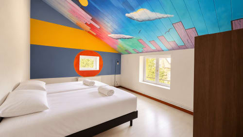 Modern bedroom at Maison Agami with colorful ceiling art, white bed, and bright windows in Rosières aux salines