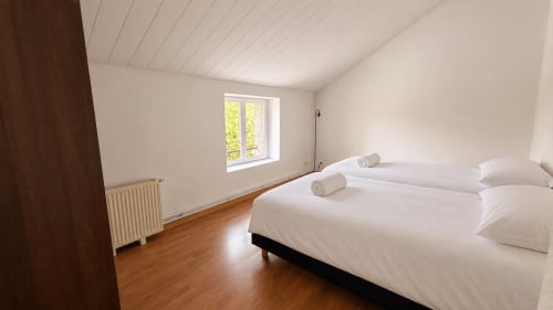 Bright attic bedroom at Maison Agami with twin beds, wooden floor, window, and radiator in Rosières aux salines