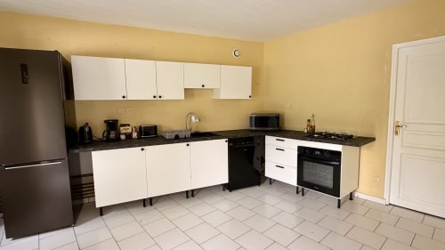 Modern kitchen with white cabinetry, black countertops, and stainless steel appliances at Maison Agami, Rosières aux salines