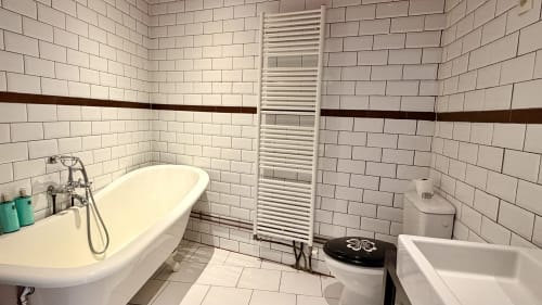 Maison Léon bathroom at Maison Agami with white subway tile, freestanding bathtub, heated towel rack, and shared toilet