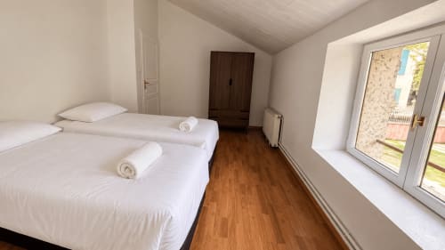 Chambre lumineuse avec deux lits simples, parquet, portes vitrées donnant sur la piscine de la villa Maison Agami