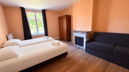 Chambre spacieuse de la villa Maison Agami avec lit blanc, canapé noir, cheminée et murs couleur pêche
