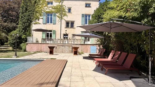 Piscine extérieure chauffée et espace lounge à la villa Maison Agami à Rosières aux Salines, avec parasols et terrasse en pierre