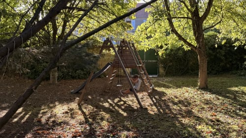 Aire de jeux ombragée avec toboggan en bois et structure d'escalade entourée d'arbres matures à la villa Maison Agami à Rosières aux