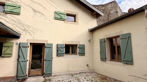 Villa de couleur crème à la Maison Agami avec volets verts et porte en bois, Rosières aux salines