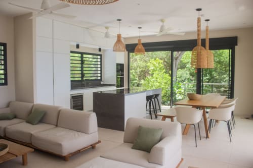 Villa contemporaine aux Anses : salon ouvert, sièges beige, salle à manger, cuisine et terrasse vue mer