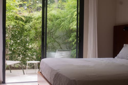 Chambre de la Villa Mahogany à INHÉRENCE Martinique avec lit, portes-fenêtres vue jardin et végétation tropicale, Les Anses