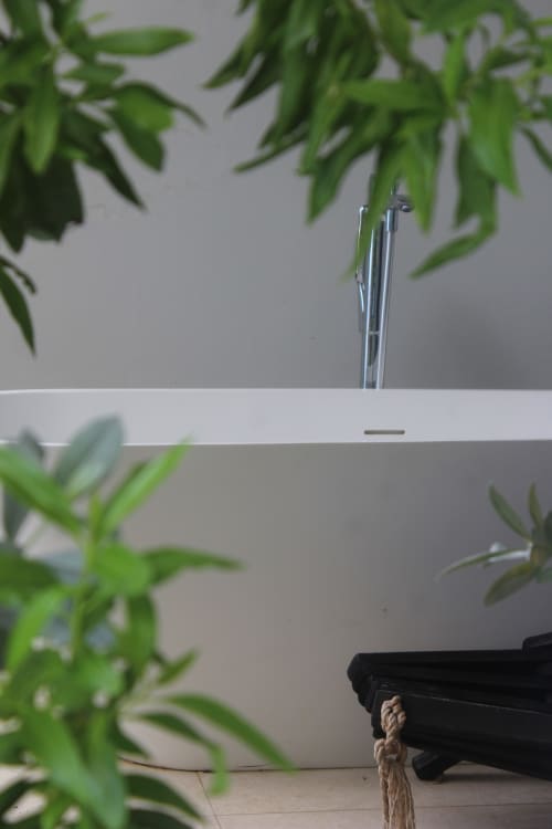 Lavabo blanc moderne avec robinetterie chromée entouré de feuillage vert frais à l'hôtel INHÉRENCE