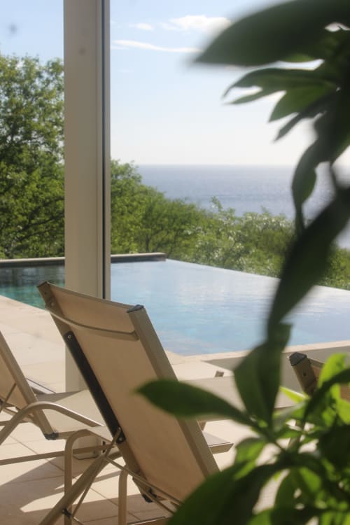 Chaises longues en bord de mer surplombant la piscine à débordement et l'océan à l'hôtel INHÉRENCE en Martinique