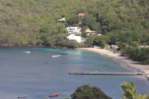 Vue aérienne de l'hôtel INHÉRENCE nichée en forêt luxuriante surplombant une baie turquoise avec bateaux à Le Lamentin, Martinique