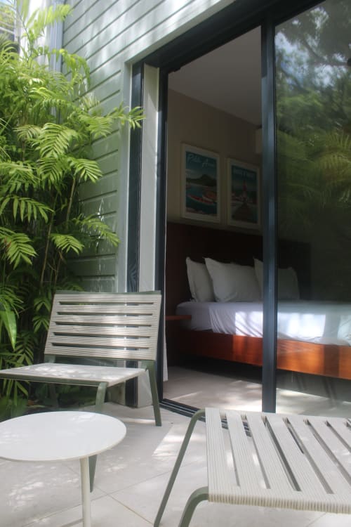 Terrasse de chambre moderne à l'hôtel INHÉRENCE au Lamentin avec chaises longues, plantes tropicales et portes vitrées donnant sur