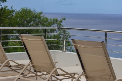 Chaises longues beige sur la terrasse avec vue sur la mer de l'hôtel INHÉRENCE au Lamentin, Martinique