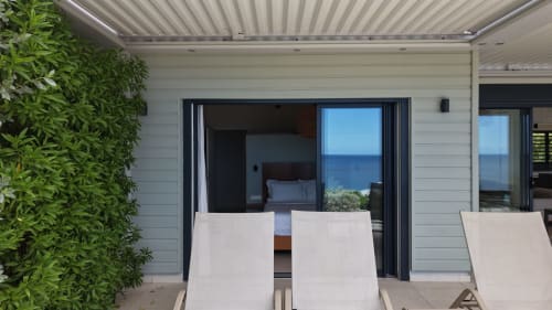 Terrasse moderne en bord de mer à l'hôtel INHÉRENCE au Lamentin avec chaises longues, vue sur la mer et accès aux chambres