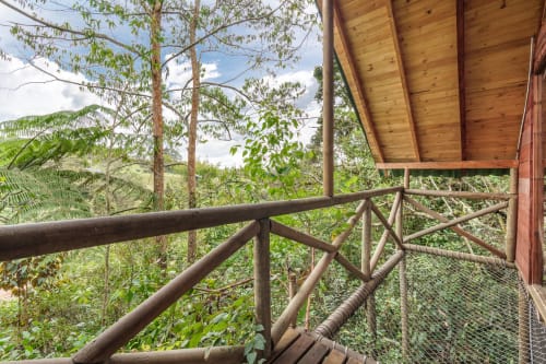 Terraza de madera con barandal con vistas al exuberante jardín de la habitación Arrayanes en Sukha Glamping, Ríonegro