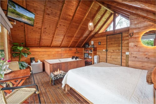 Lujosa habitación de cabaña de madera con cama, bañera de hidromasaje y vistas al jardín en Sukha Glamping en Ríonegro