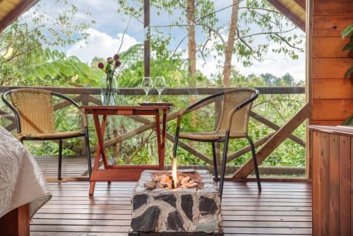 Balcón de Sukha Glamping con sillas de mimbre, fogata y vistas al jardín exuberante en Ríonegro