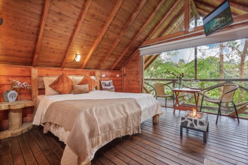 Dormitorio Sukha Glamping Arrayanes con mobiliario de madera, vistas al jardín, asientos en balcón y terraza con vista a la naturaleza