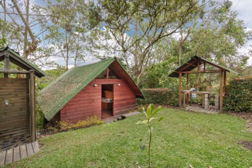 Cabaña glamping roja con techo verde rodeada de exuberante jardín en Sukha Glamping, Ríonegro, Colombia