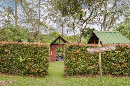 Habitación Arrayanes en Sukha Glamping de Ríonegro con vistas al exuberante jardín, setos y arquitectura tradicional
