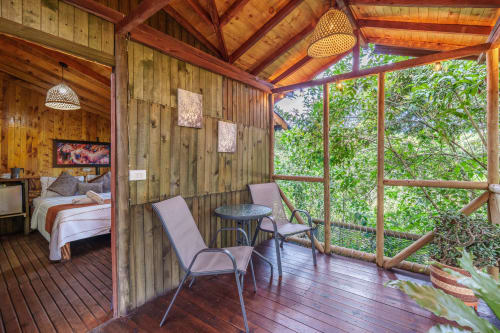 Habitación Eucalipto en Sukha Glamping con terraza de madera, vista al jardín, tumbonas y dormitorio con TV