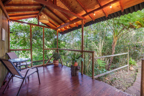 Terraza de madera en Sukha Glamping con tumbonas, plantas en macetas y vistas al bosque a través de la barandilla