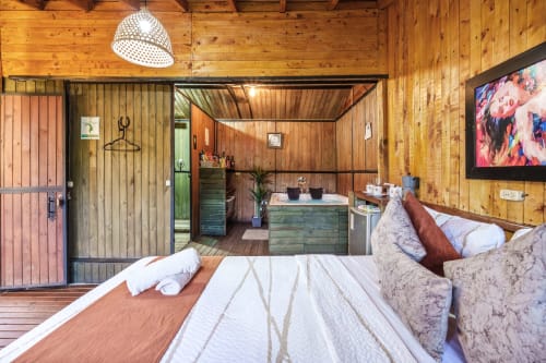 Habitación Eucalipto en Sukha Glamping de Ríonegro con interior de madera, cama con sábanas blancas, baño privado y TV