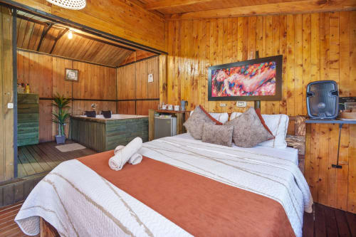 Habitación Eucalipto en Sukha Glamping de Ríonegro con paredes de madera, cama confortable, TV y baño privado con ducha de agua caliente