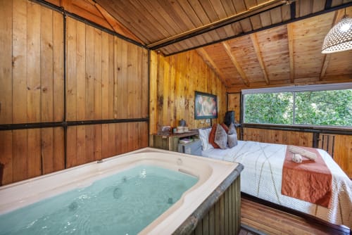 Habitación Eucalipto en Sukha Glamping con bañera de hidromasaje, cama, TV y vistas al jardín en cabaña de madera