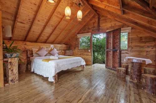 Habitación de cabaña Yarumo en Sukha Glamping, Ríonegro, con cama, lámparas colgantes y vistas al jardín