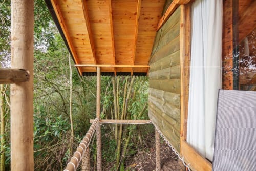 Pasillo de la habitación de glamping de madera con vegetación del jardín en Sukha Glamping, Ríonegro Colombia