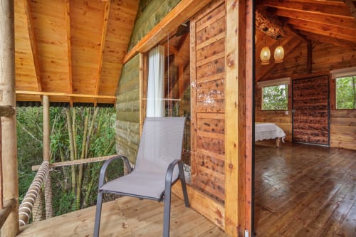 Patio de la habitación Yarumo en Sukha Glamping de Ríonegro con terraza de madera, silla de descanso y vistas al jardín