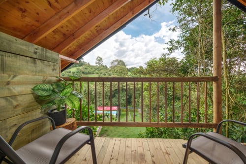 Terraza de madera en Sukha Glamping con sillas con vistas a jardines exuberantes y campiña verde en Ríonegro, Colombia