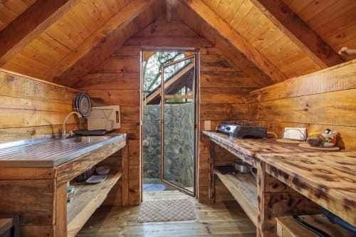 Interior de cabaña de madera Sukha Glamping Yarumo con cocina, estantes y puerta de cristal hacia el jardín en Ríonegro