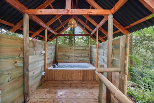 Cabaña de lujo de madera con bañera de hidromasaje en Sukha Glamping, Ríonegro, Colombia, rodeada de exuberante vegetación
