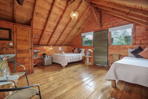 Amplio dormitorio de cabaña de madera en Sukha Glamping con dos camas, vistas al jardín, techo abovedado y comodidades modernas